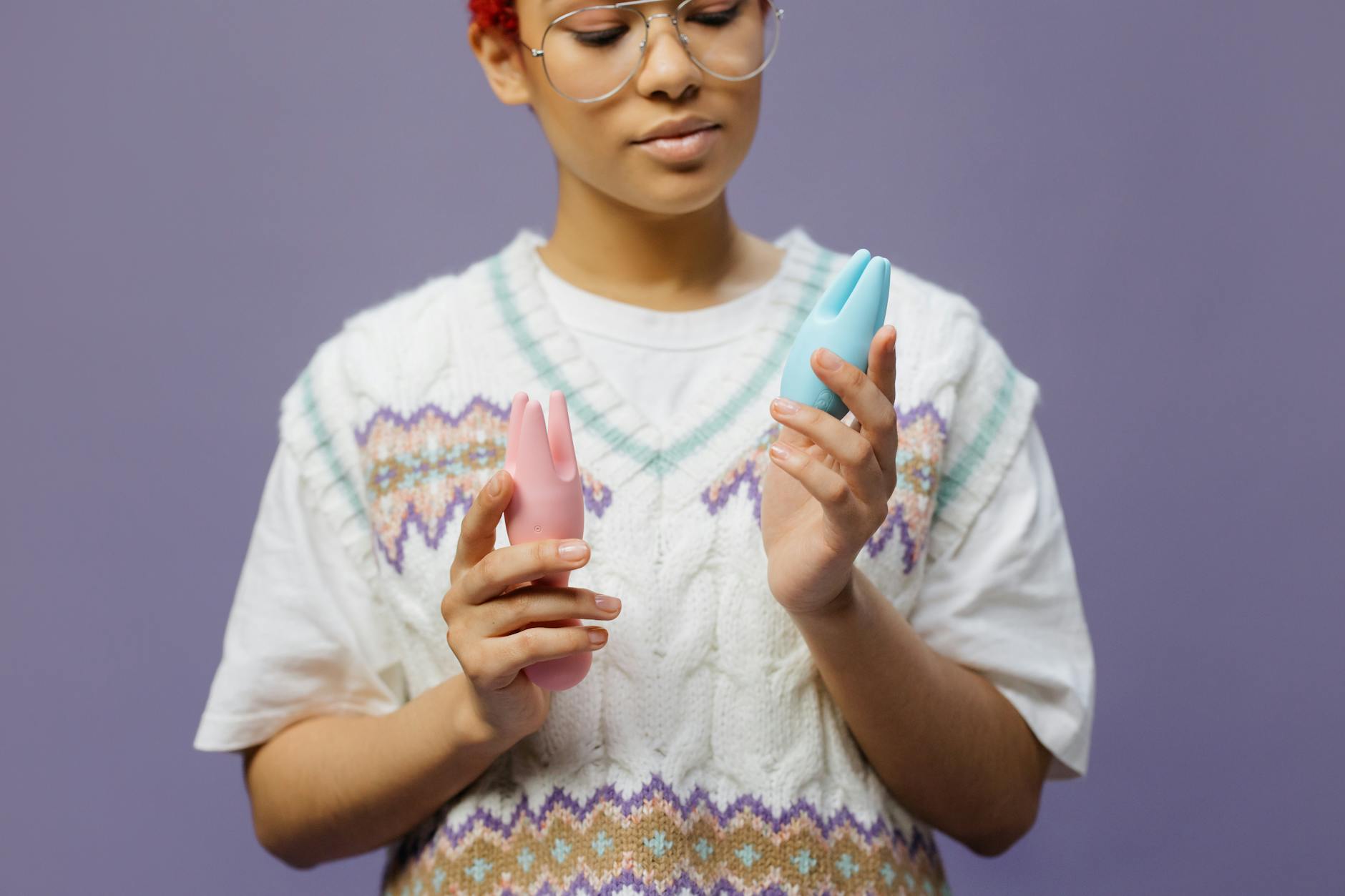 Woman contemplating her options with blue and pink silicone vibrators in a supportive, thoughtful setting.