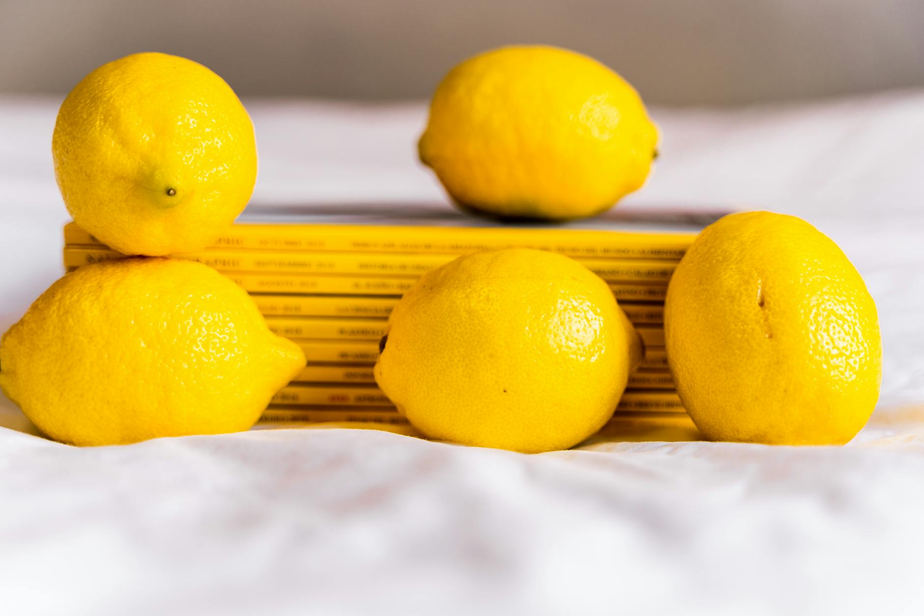 Hand holding a fresh lemon against a bright yellow background, representing the lemon vibrator concept